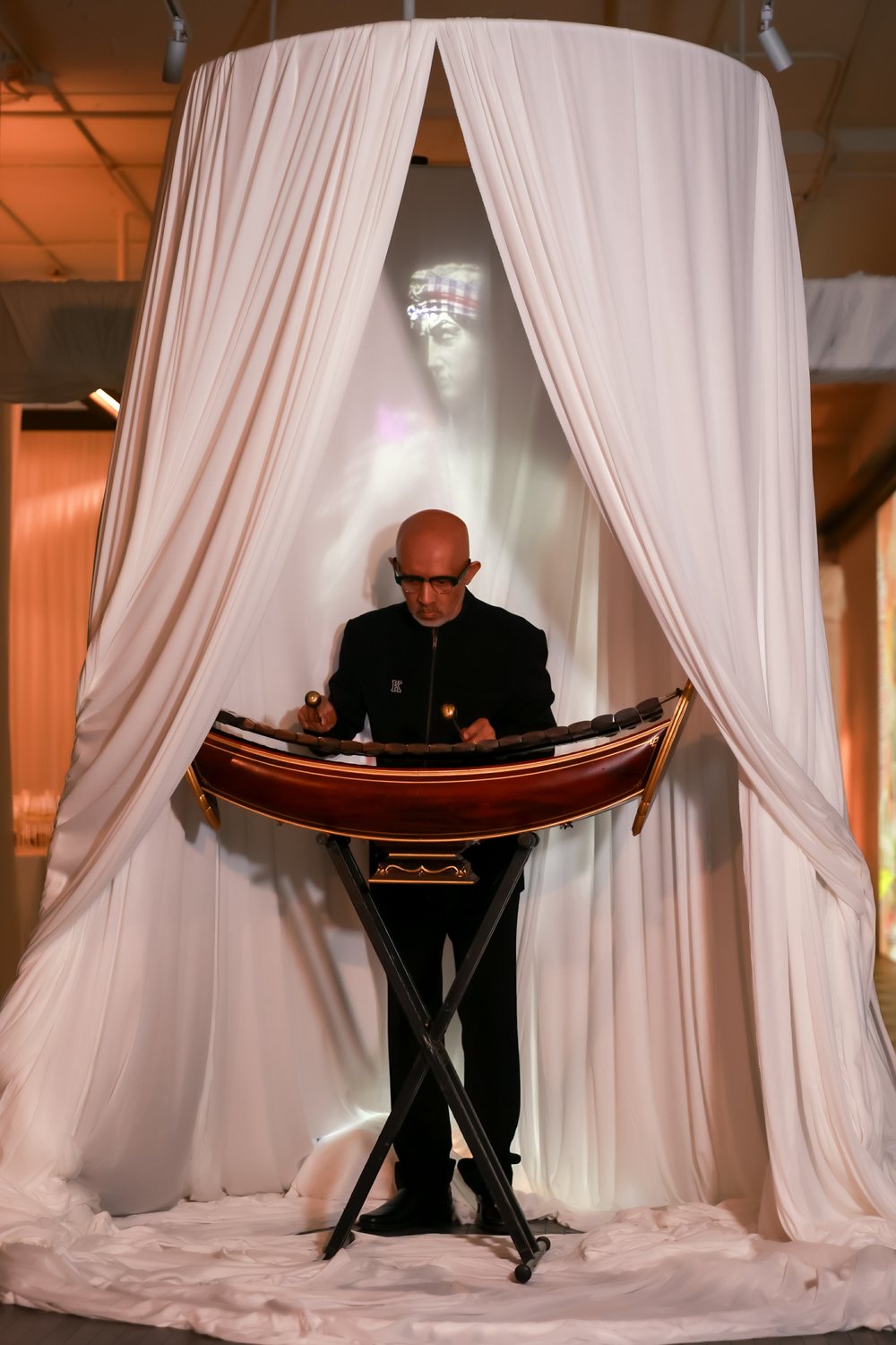 Master ranat player Ajarn Khun In Narong Tosanga performing inside a white drape at The Legacy of Motion, Bonaldo Space by OL Atelier, Bangkok