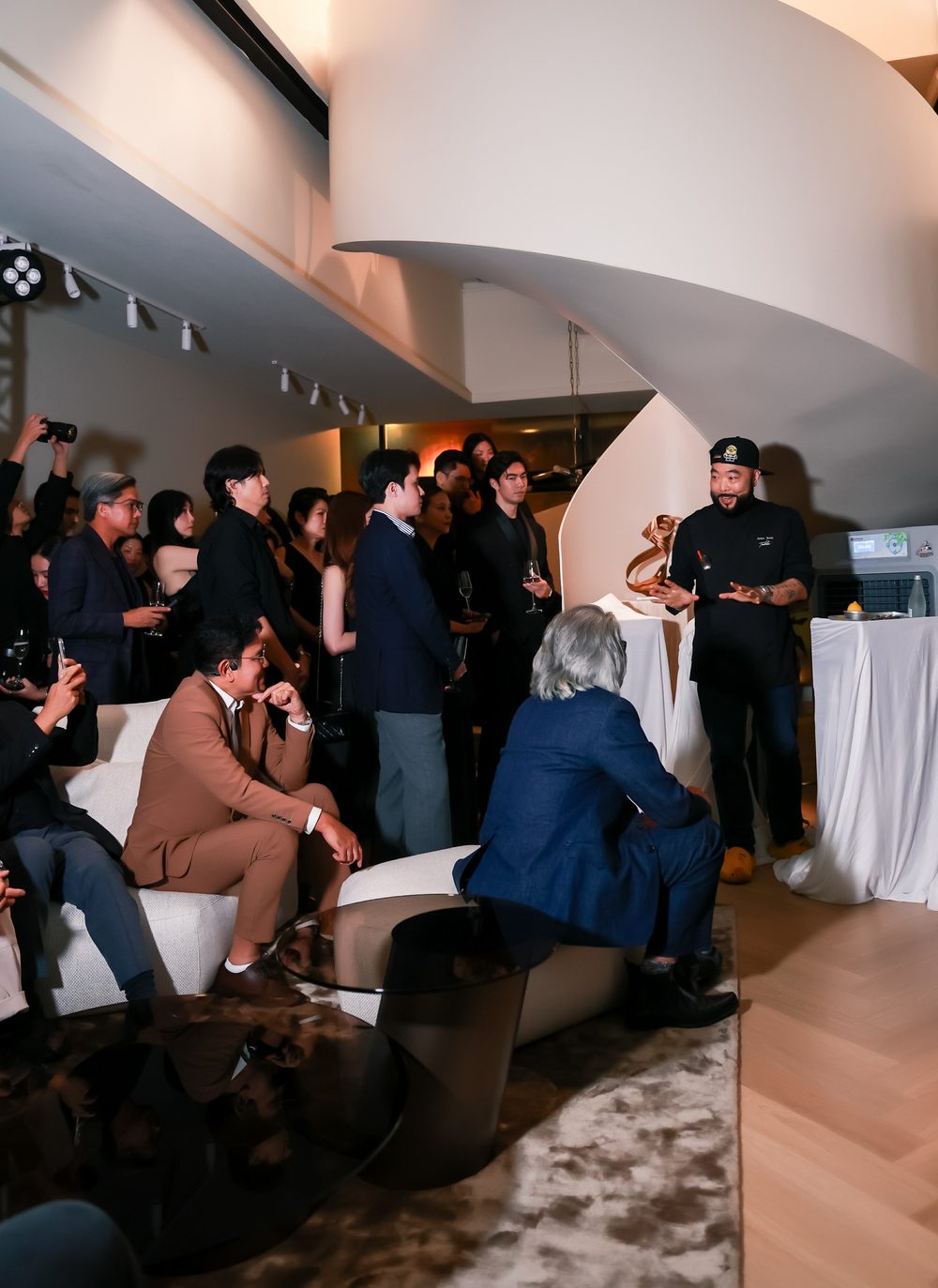 Chef Andy Yang speaking to seated guests beside the white sculptural staircase at The Legacy of Motion, Bonaldo Space by OL Atelier, Bangkok