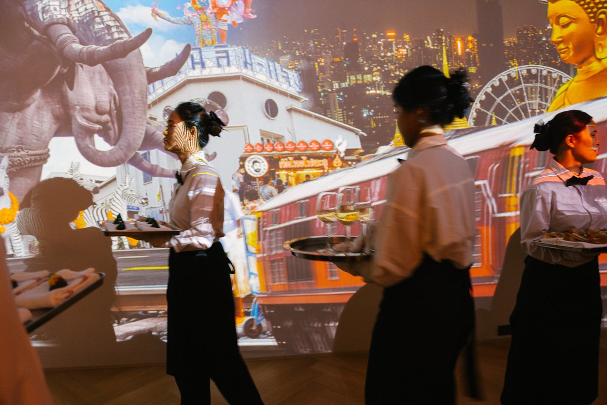 Waiters carrying trays in front of the Bangkok projection mapping at The Legacy of Motion, Bonaldo Space by OL Atelier, Bangkok